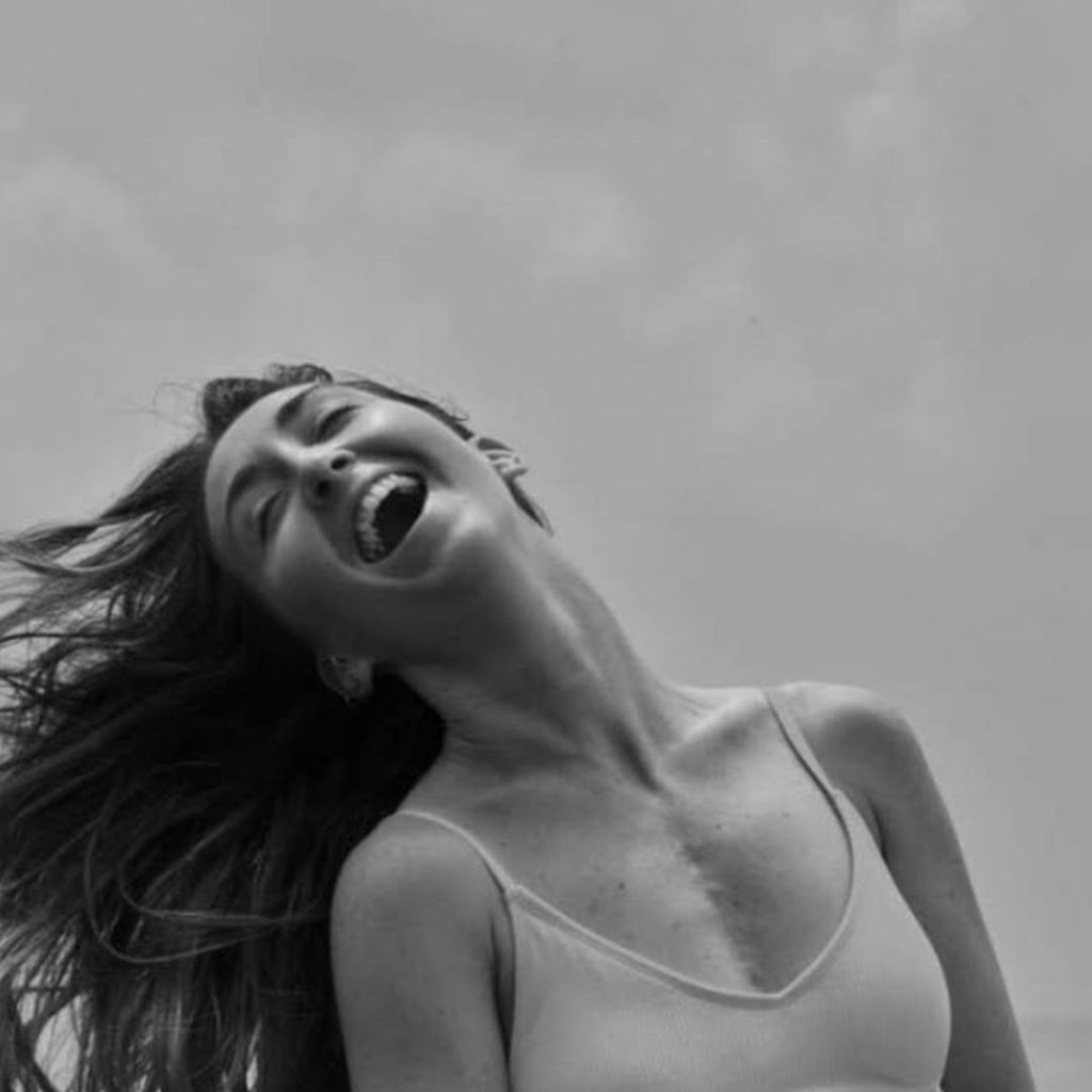 A black-and-white image of Laura laughing, with her open-heart surgery scar visible.